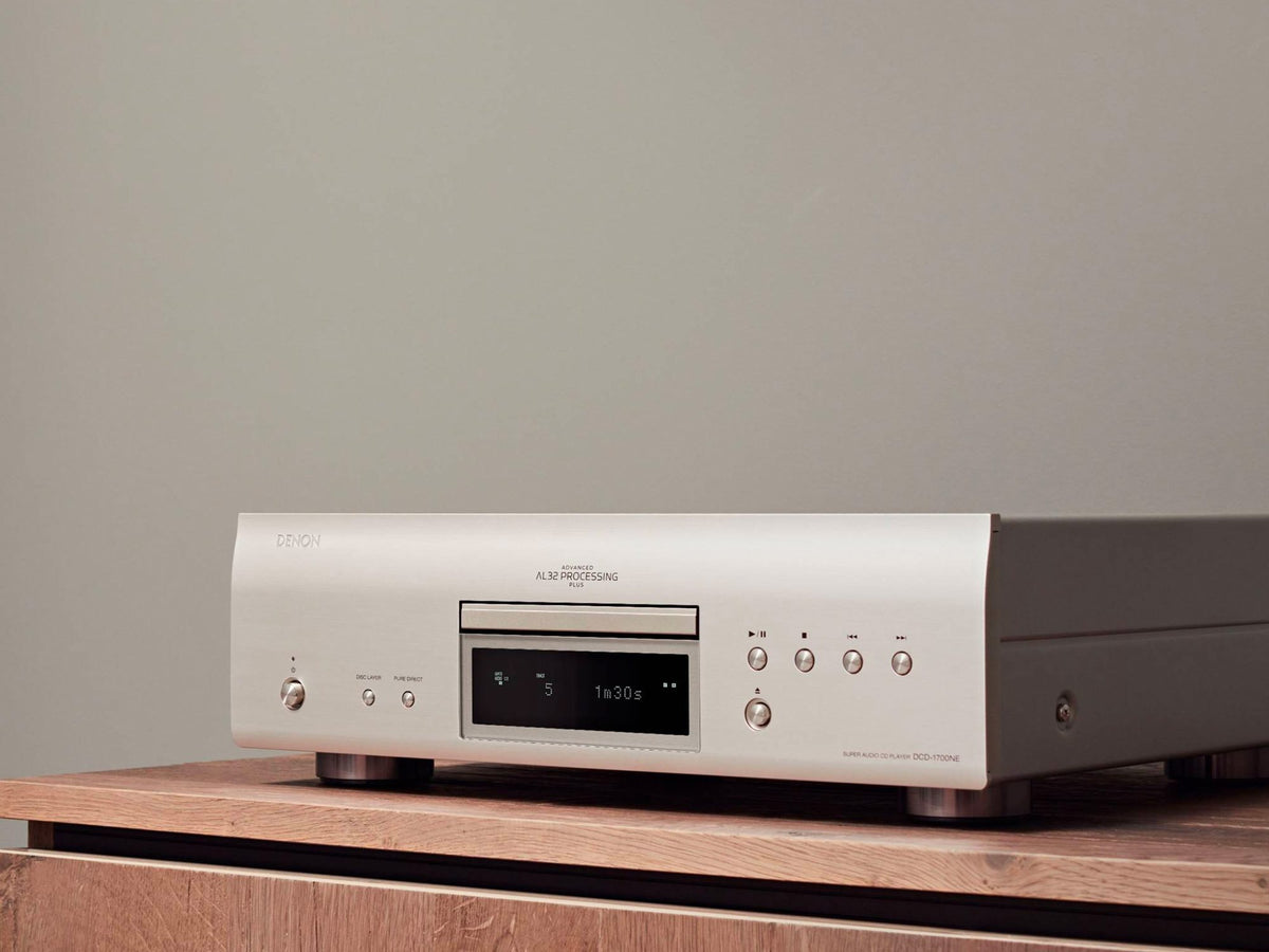 Denon DCD-1700NE CD/SACD player: silver player on a wooden cabinet, left angled view