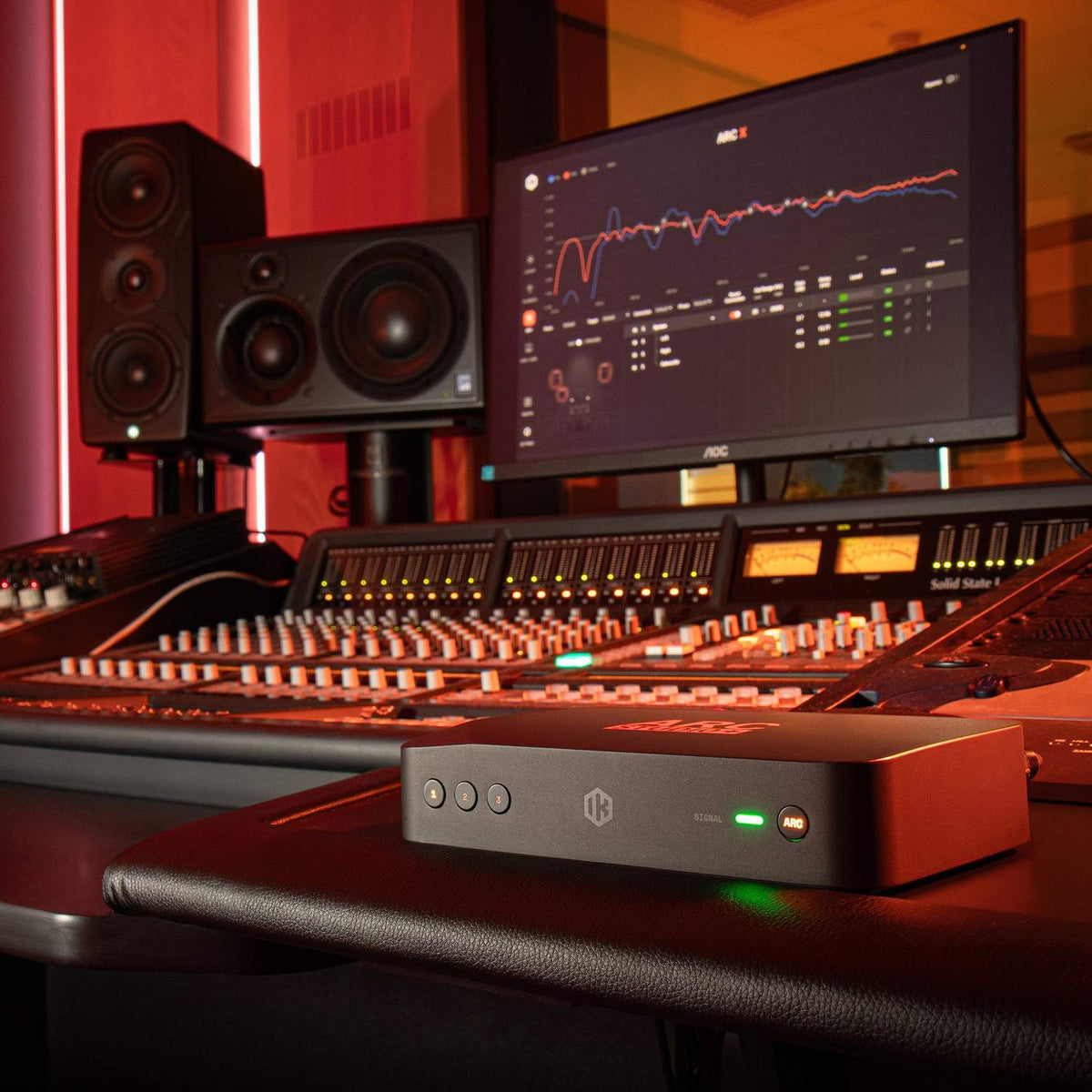 IK Multimedia ARC STUDIO+ Room Correction System beside a studio mixing console