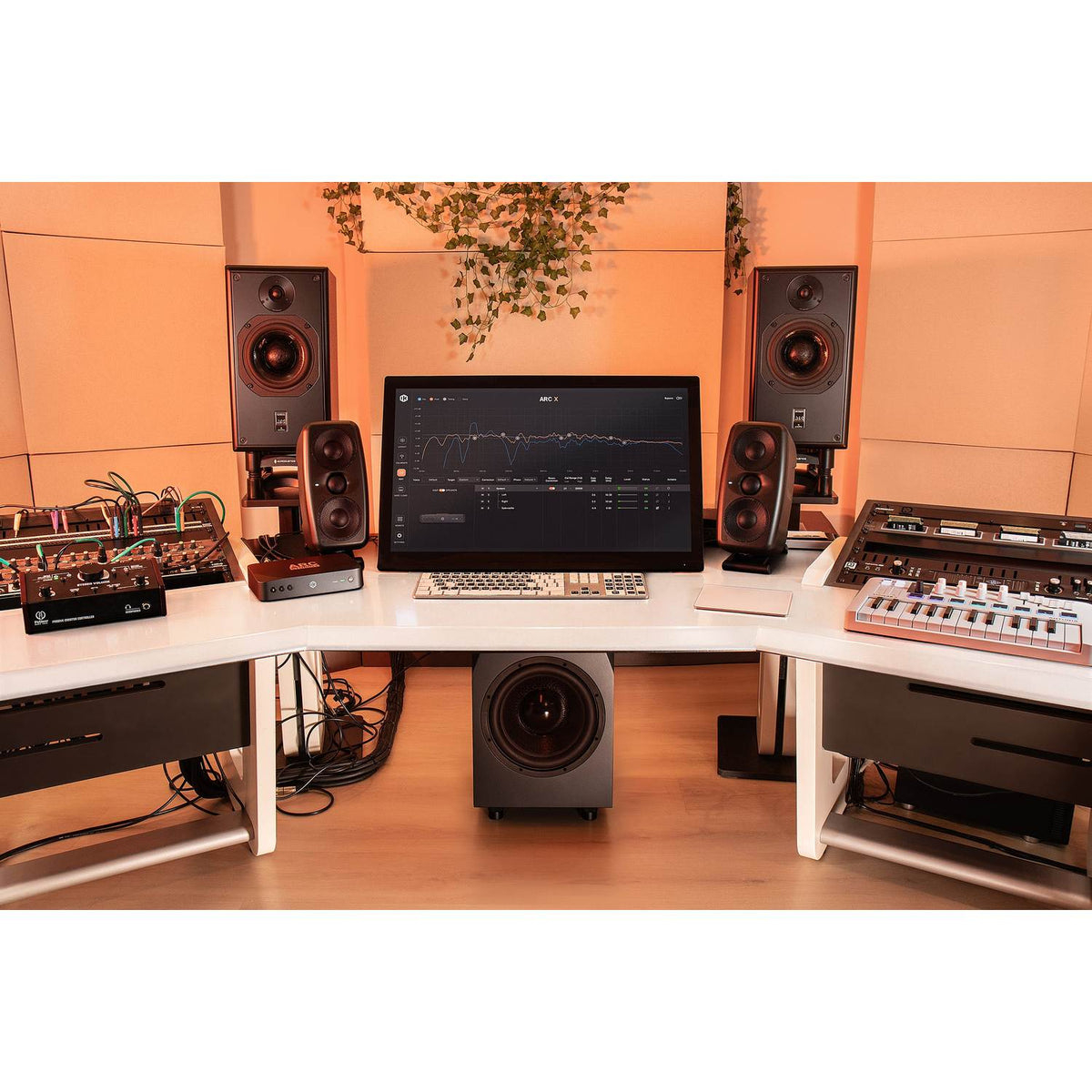 IK Multimedia ARC STUDIO+ Room Correction System in a studio with monitors and a subwoofer